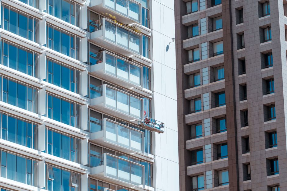 Close-up view of modern skyscraper facades featuring balconies and windows with suspended scaffold.